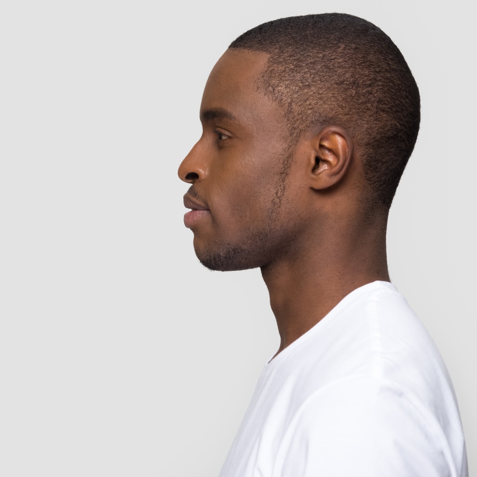 Millennial african american man standing in profile isolated on blank white grey studio background, confident black guy looking forward at copy space thinking of future leadership, side view portrait