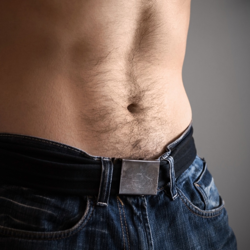 Sporty male belly with jeans. Closeup photo, shallow depth of field