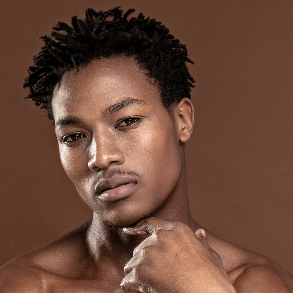 Fit young man looking at camera, posing isolated on brown background. Naked torso of African American man posing at studio. Muscular body, fitness, sports, healthy lifestyle and bodybuilder concept.