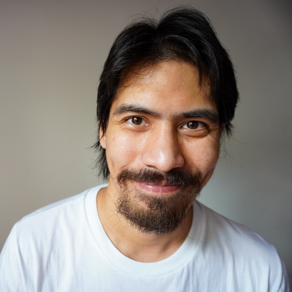 Portrait of handsome Asian Latino guy smiling, looking straight to the camera. Studio shooting concept of happy, attractive, masculine casual male. Copy space with a gray background.