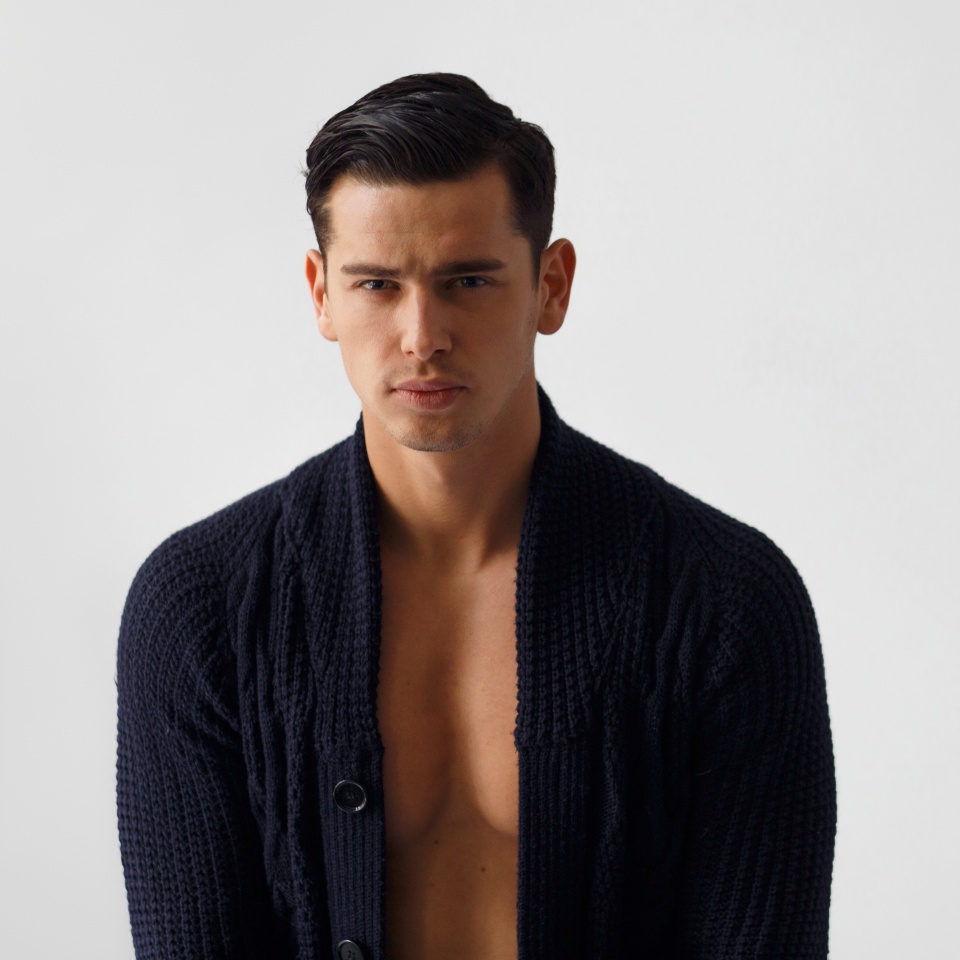 Front portrait of handsome fit brunette young man in black sweater, isolated white background. Copy space.