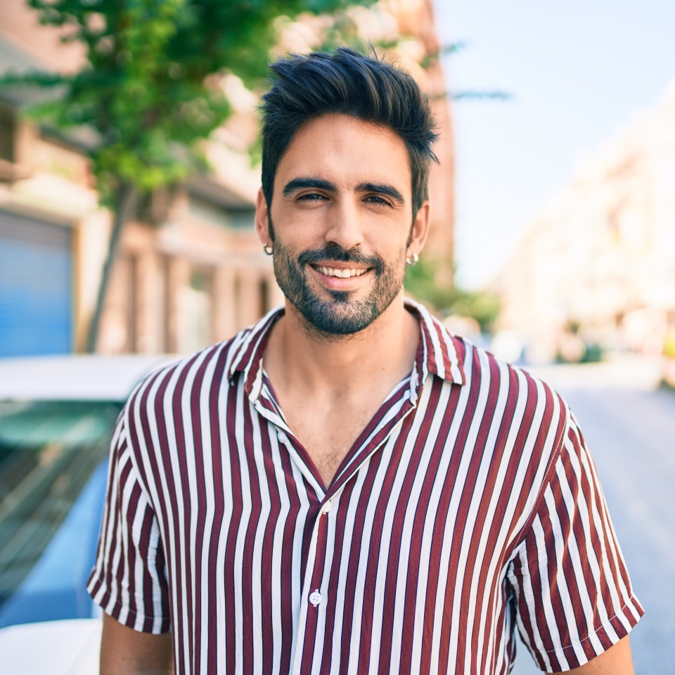Young handsome hispanic man with beard smiling happy outdoors