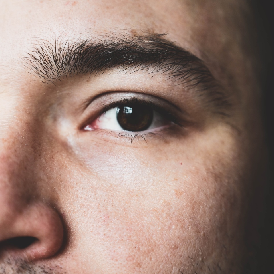 A young man stares at the camera. Brown man's eyes close up. Male face close up.