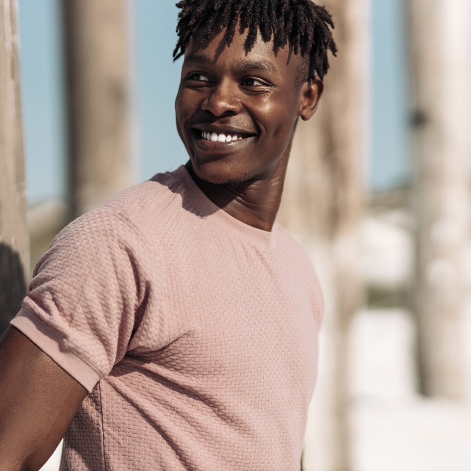 Close up portrait of handsome contented african man, with afro hair, smiling broadly, laughing outdoors