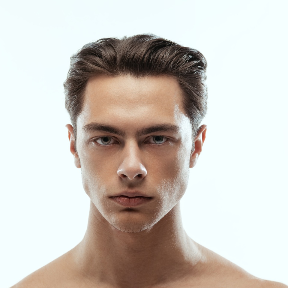 Close-up portrait of young handsome man isolated on white studio background. Concept of men's health and beauty, self-care, body and skin care. Male model looking at camera