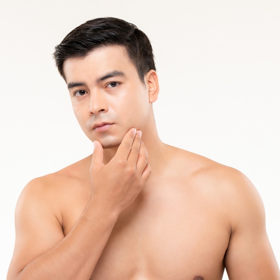 Handsome man touching his face checking for skin problems and wrinkles in white isolated background