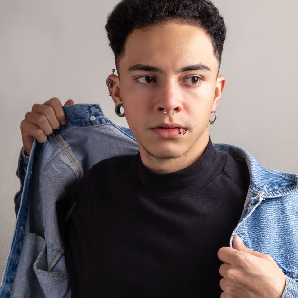 Model Young man with piercings, with curly hair and confident pose wearing a denim jacket