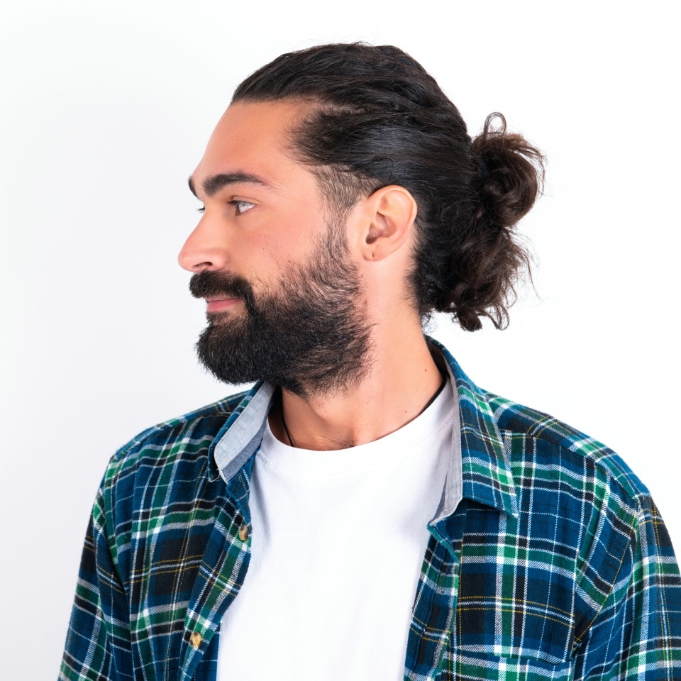 Side view of young happy smiling young hispanic bearded man wearing plaid shirt over white background