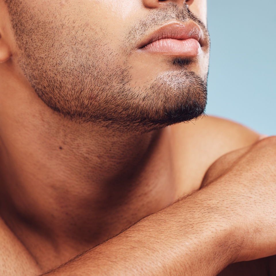 Man, jaw and skincare, face grooming and beard for beauty, aesthetic wellness and healthy skin on studio blue background. Closeup of handsome guy model, facial hair and dermatology body cosmetics