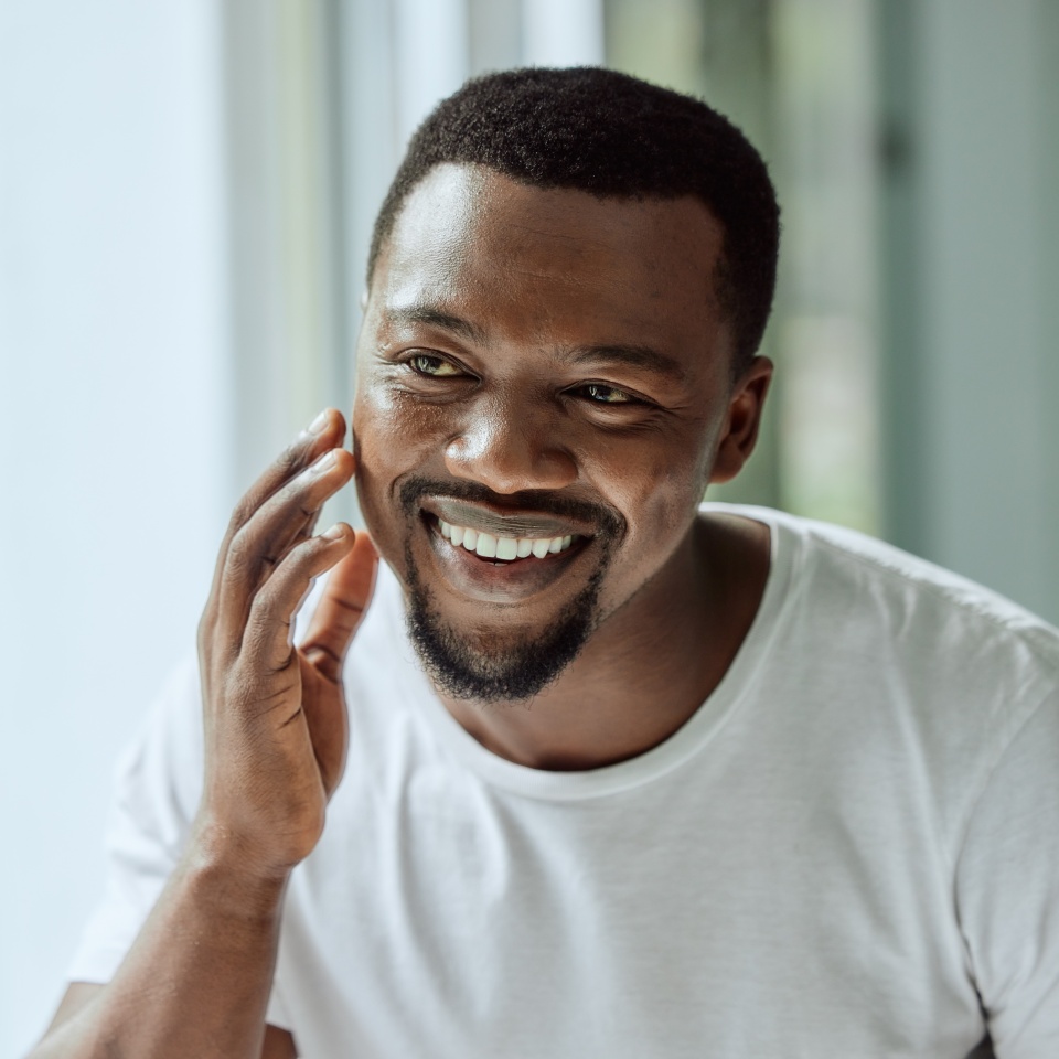 Face, antiaging and skin with a black man looking in the bathroom mirror during his morning routine at home. Skincare, beauty and reflection with a handsome male grooming for wellness or natural care