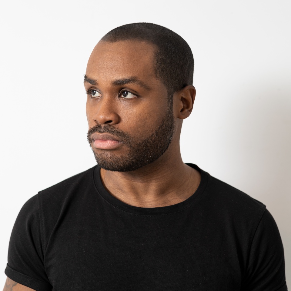 Three-quarters portrait of an attractive African-American millennial man, a handsome young man in a black T-shirt, a serious boy, a student posing nearby isolated on the white background.