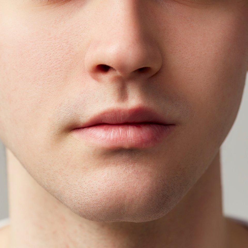 Cropped image of male face nose, lips, chin. Young model posing over grey studio background. Well-kept skin. Concept of men's health, body and skin care, hygiene and male cosmetology