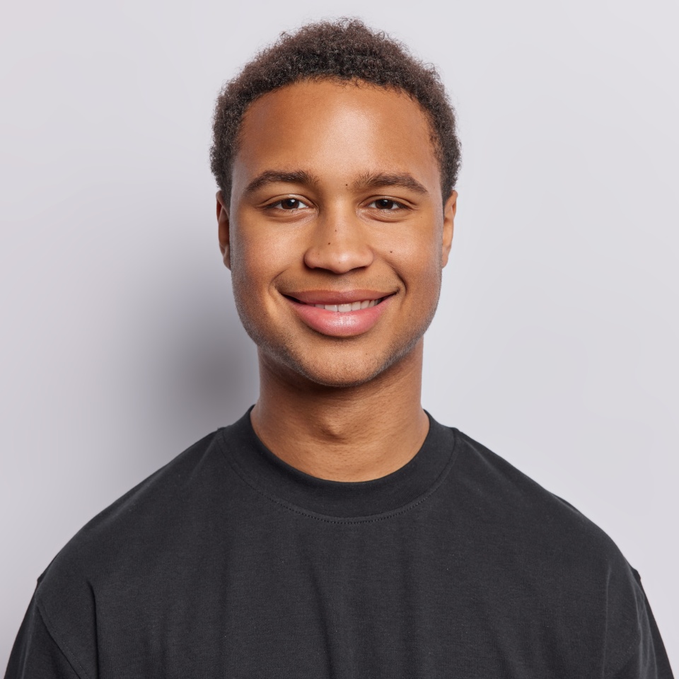 Portrait of contented dark skinned man with short curly hair radiates satisfaction upon hearing good news exudes pure satisfaction wears black t shirt isolated over white background. Emotions concept
