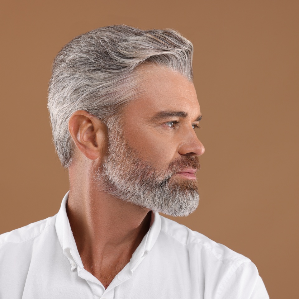 Portrait of confident man with beautiful hairstyle on light brown background. Space for text