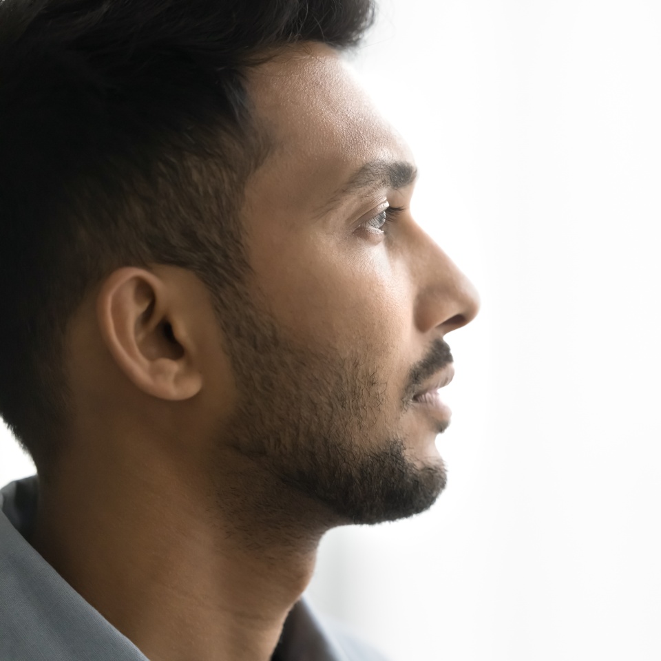 Close up profile face view of pensive Indian man with attractive appearance, well-groomed beard looks into distance posing on white grey copy space background for your text. Thoughts, memories, quotes