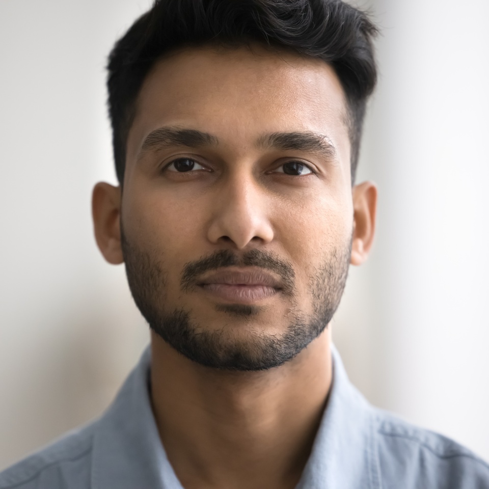 Close up of unsmiling Indian bearded guy standing indoor staring at camera. Man having attractive appearance, looks confident and serious. Millennial generation person, businessman head shot portrait
