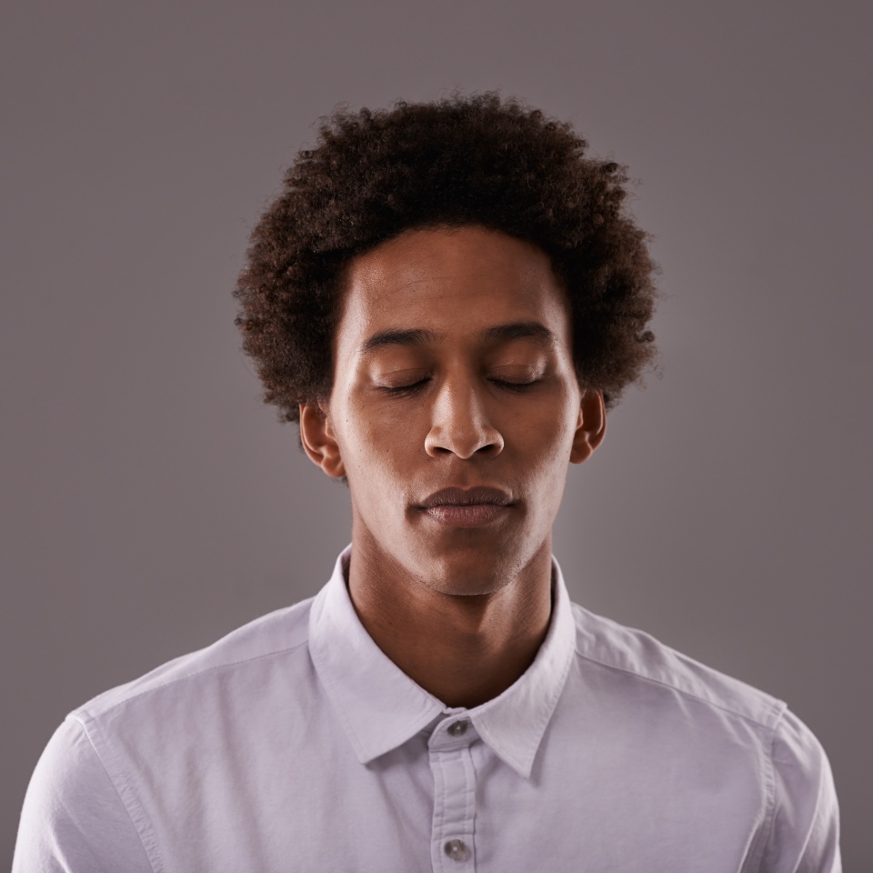 Eyes closed, calm and face of black man in studio with breathing, zen or peace for anxiety. Relax, mental health and African male person with dreaming face expression isolated by gray background.