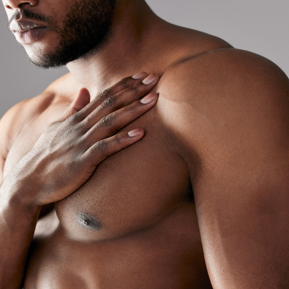 Hand, chest and black man in studio with muscle, topless and healthy body on gray background. Male bodybuilder, fitness and strength or health for strong athlete, performance and masculine skincare