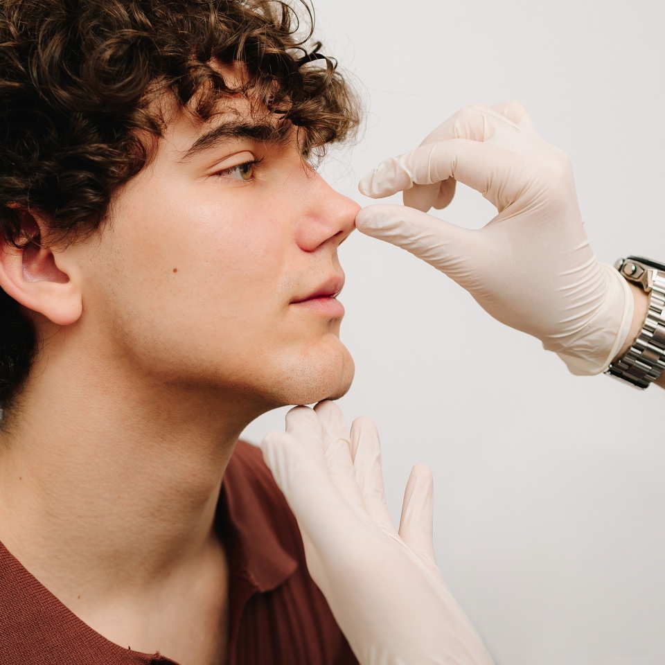 Rhinoplasty surgery preparation for man. ENT is touching nose and consulting man. Final examination before septoplasty surgery