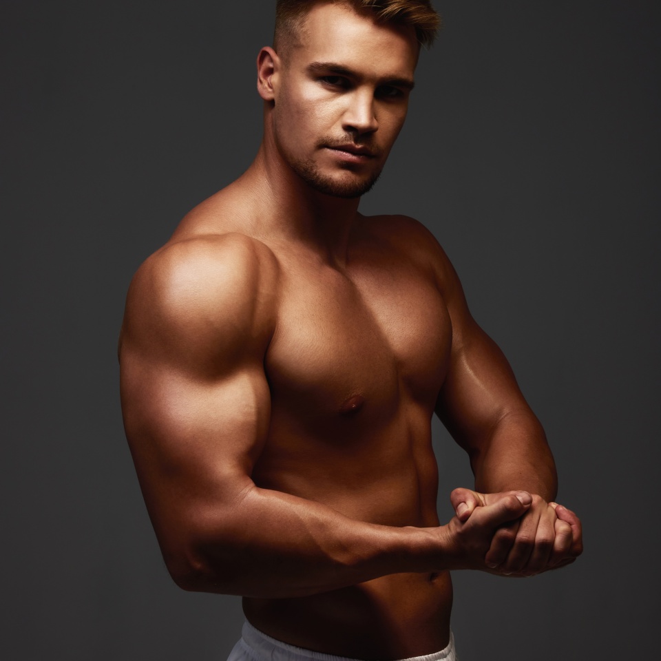 Portrait, flexing and bodybuilder in studio for exercise, training and fitness for health. Sportsman, athlete and shirtless for wellness by dark background for transformation, workout and pose