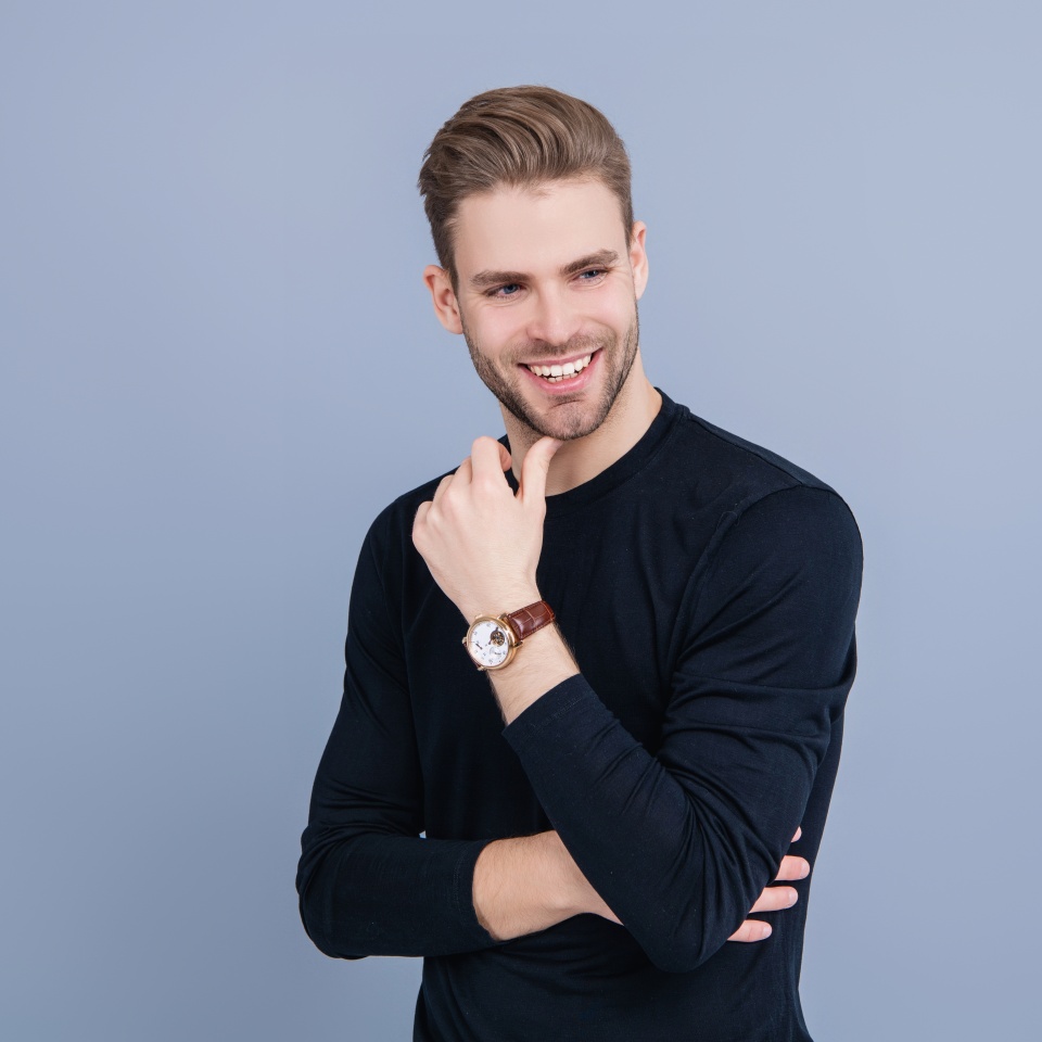Guy with confident face. Young handsome man wearing casual sweater. Unshaven man isolated on grey. Portrait of man with stylish haircut. Millennial charismatic model. Men beauty. Happy and smiling