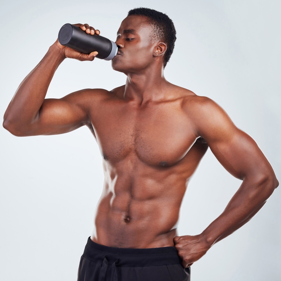 Black man, drinking and fitness with water bottle in studio for hydration or thirst on a gray background. Active African, male person or muscular model with mineral liquid for natural sustainability