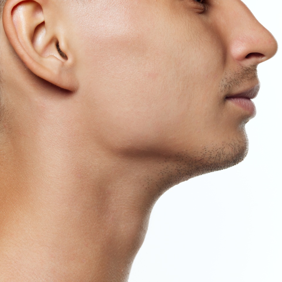 Close-up of a man's profile, focusing on his ear, jawline, and neck against white studio background. Facial features. Concept of beauty, care, cosmetology treatment, wellness, masculinity. Ad