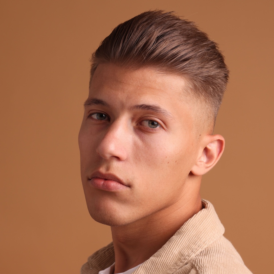 Confident young man with stylish haircut on brown background