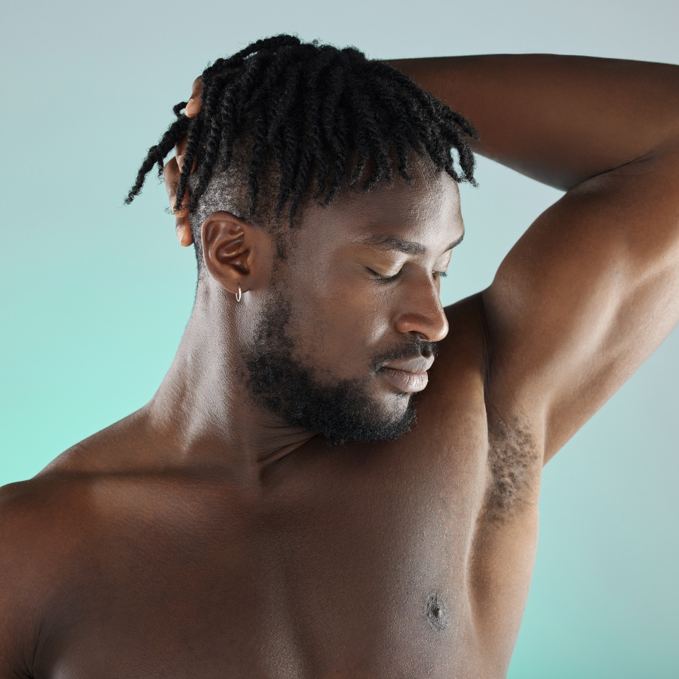 Armpit, wellness and black man with skincare hygiene or grooming isolated against a studio background. Natural, cosmetics and body care for healthy skin by a young, confident and African model