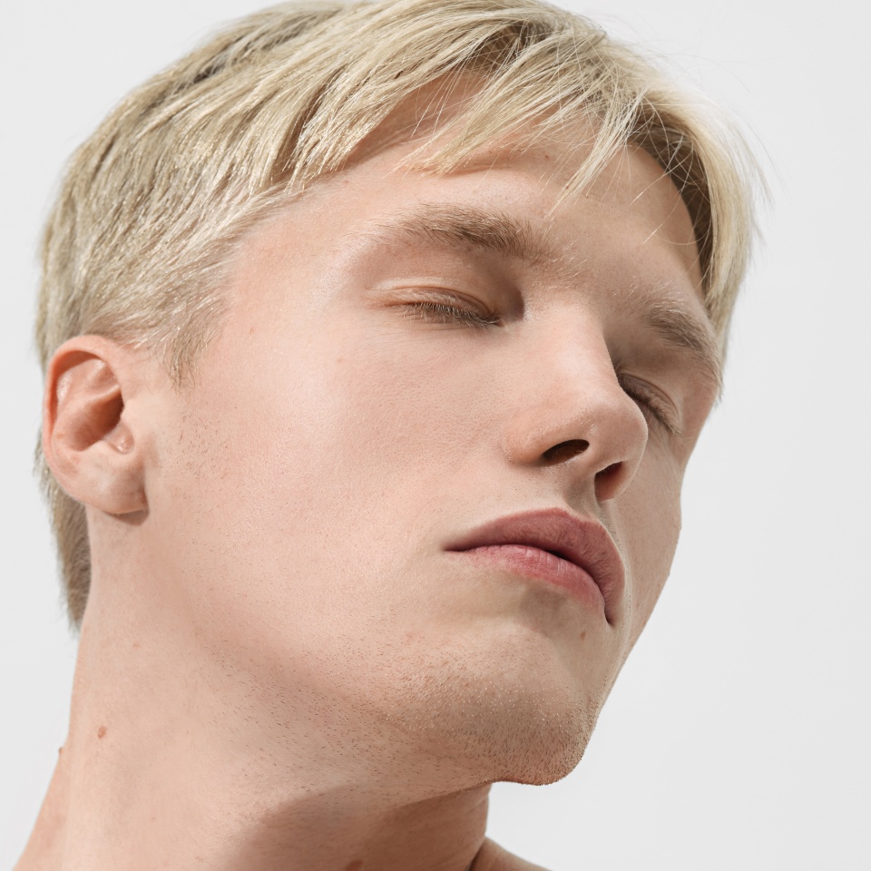 Man with eyes closed head tilted relaxed face skincare. Concept of relaxation, cosmetic brand campaign, wellness platform, barbershop style, beauty editorial, and skin health for men.