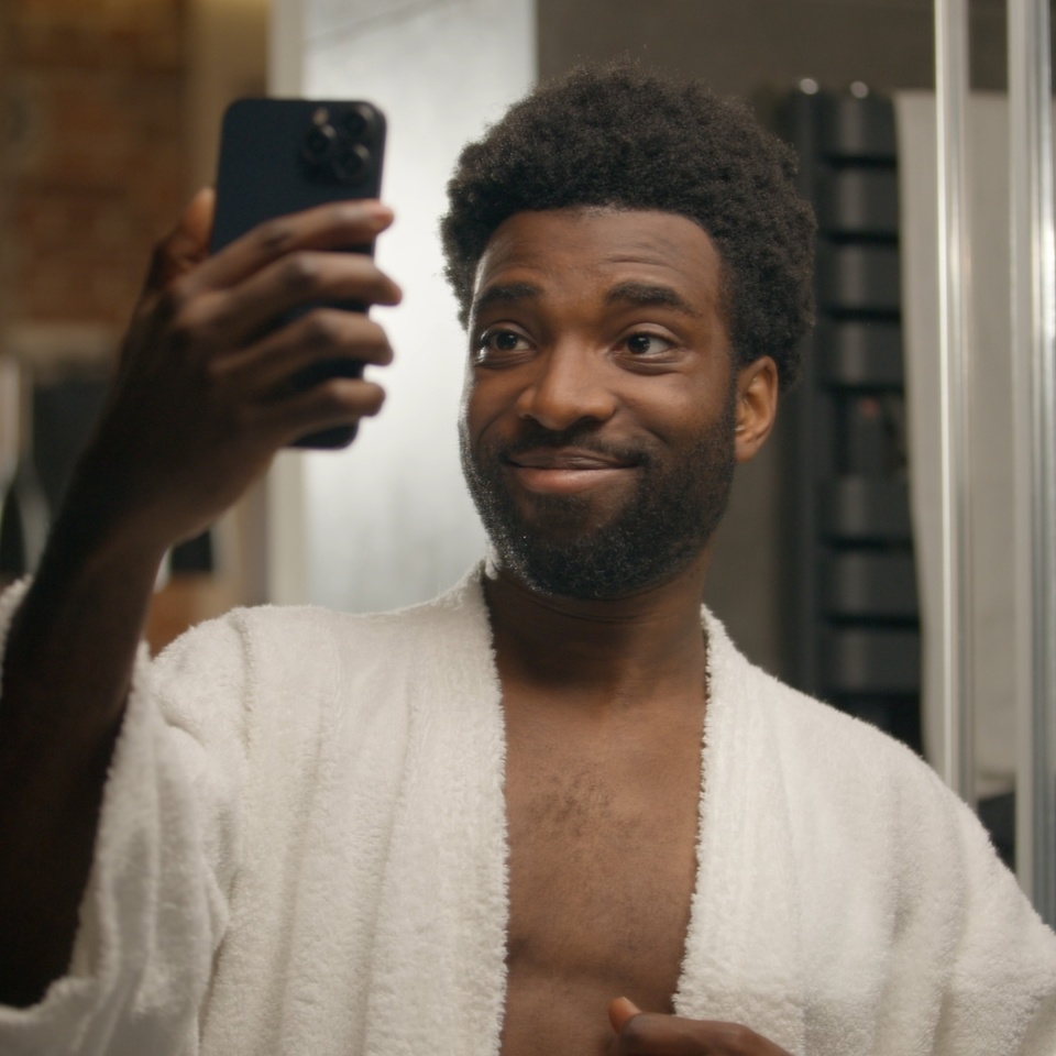 African American man blogger model influencer selfie photo mobile phone in bathroom skincare blog vlog social media handsome smiling ethnic male guy posing at home bath face cosmetics video smartphone