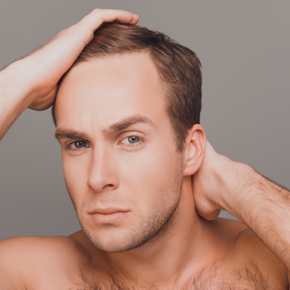 Portrait of young man combing his hair with fingers